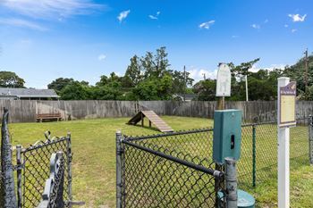 A park with a chain link fence and a seesaw in the grass